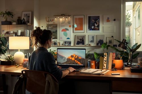 Žena sedí u pracovního stolu a pracuje na laptopu.