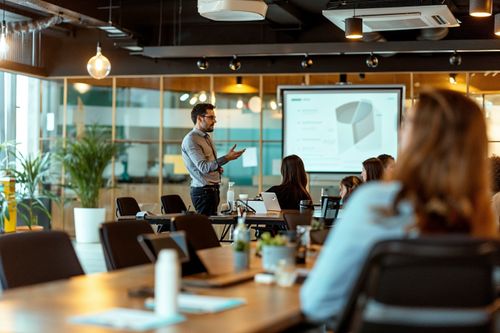 Muž prezentuje na obrazovce v zasedací místnosti.